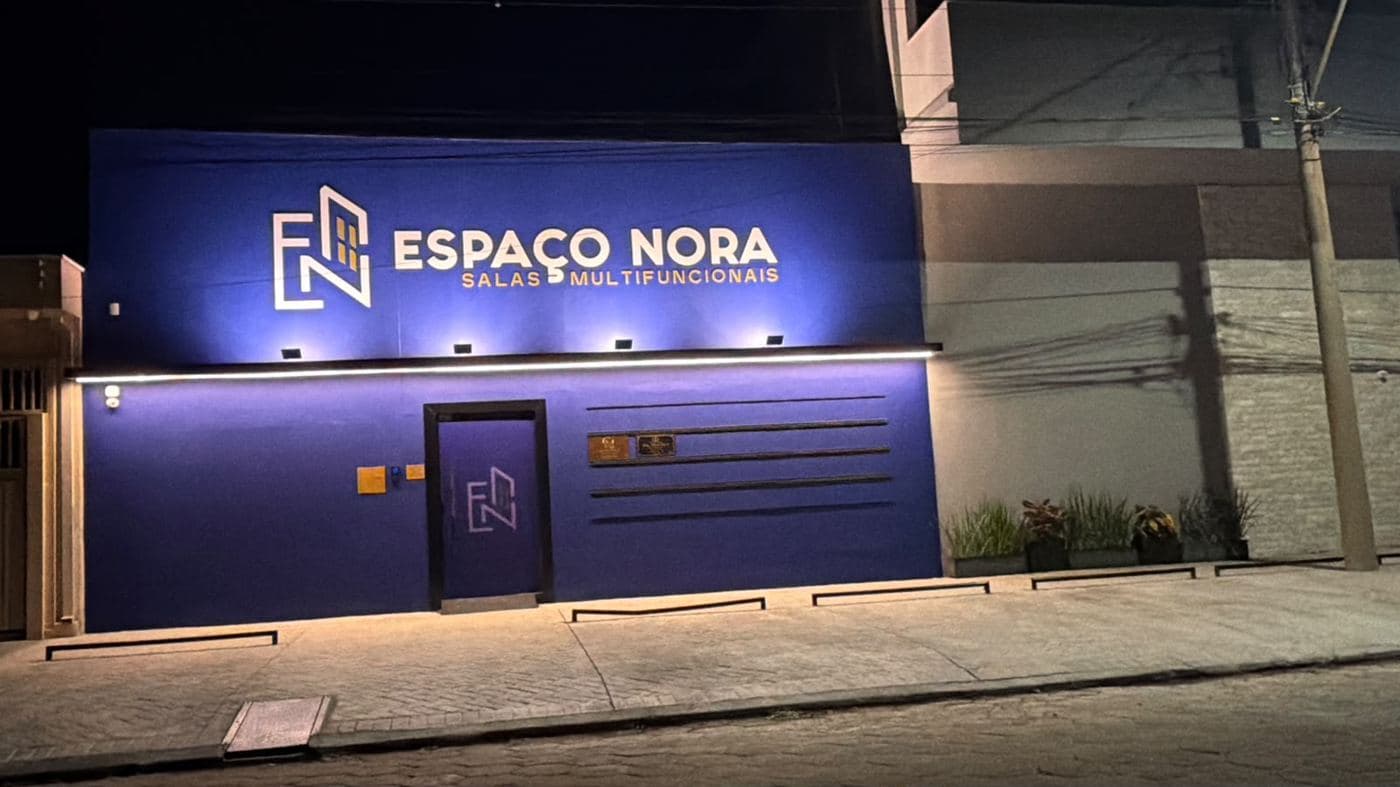 Fachada do Espaço Nora à noite, letreiro iluminado